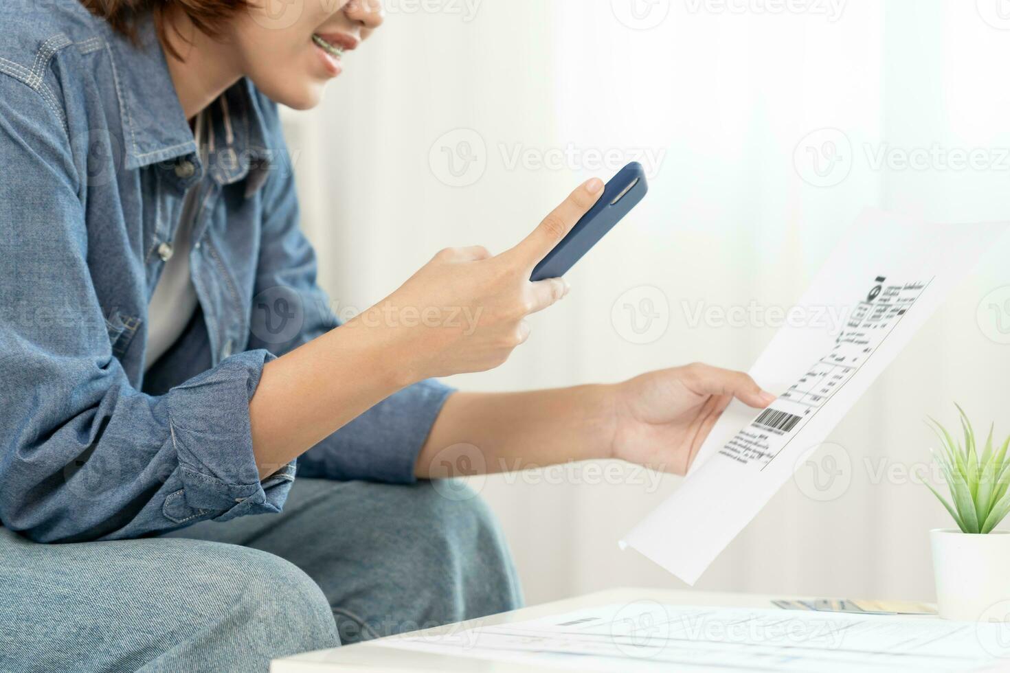 Young woman use phone to scan barcode or QR codes to pay credit card bill after receiving document invoice online. payment, receive, paying electricity, digital payments, technology, scanning photo
