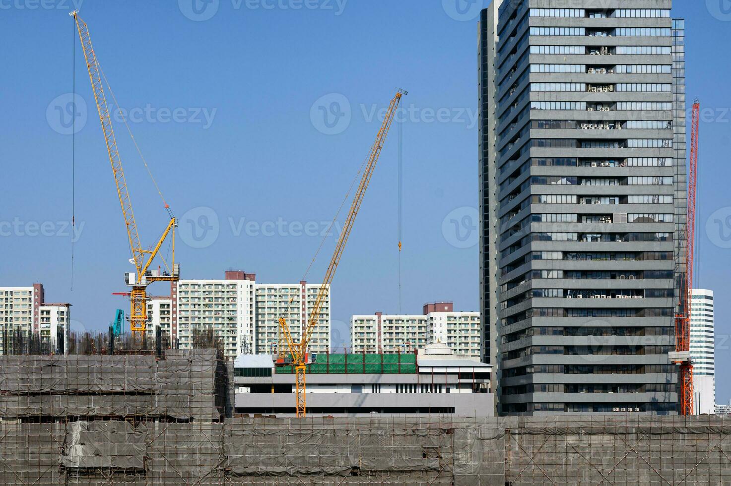 Construction site building with yellow crane and scaffolding photo