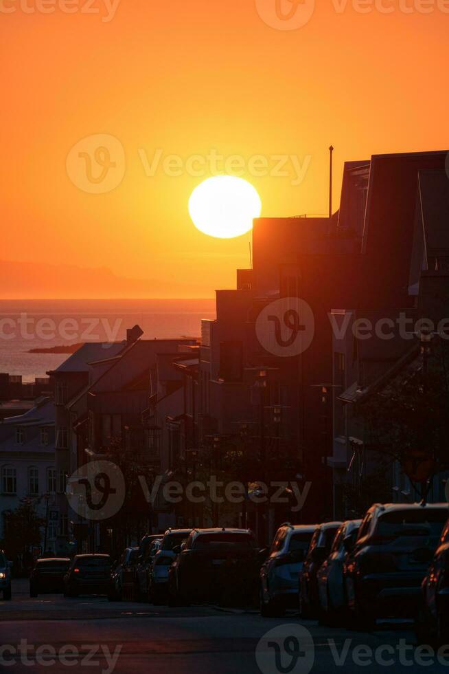 puesta de sol terminado edificio y coche estacionamiento en el borde del camino en céntrico foto