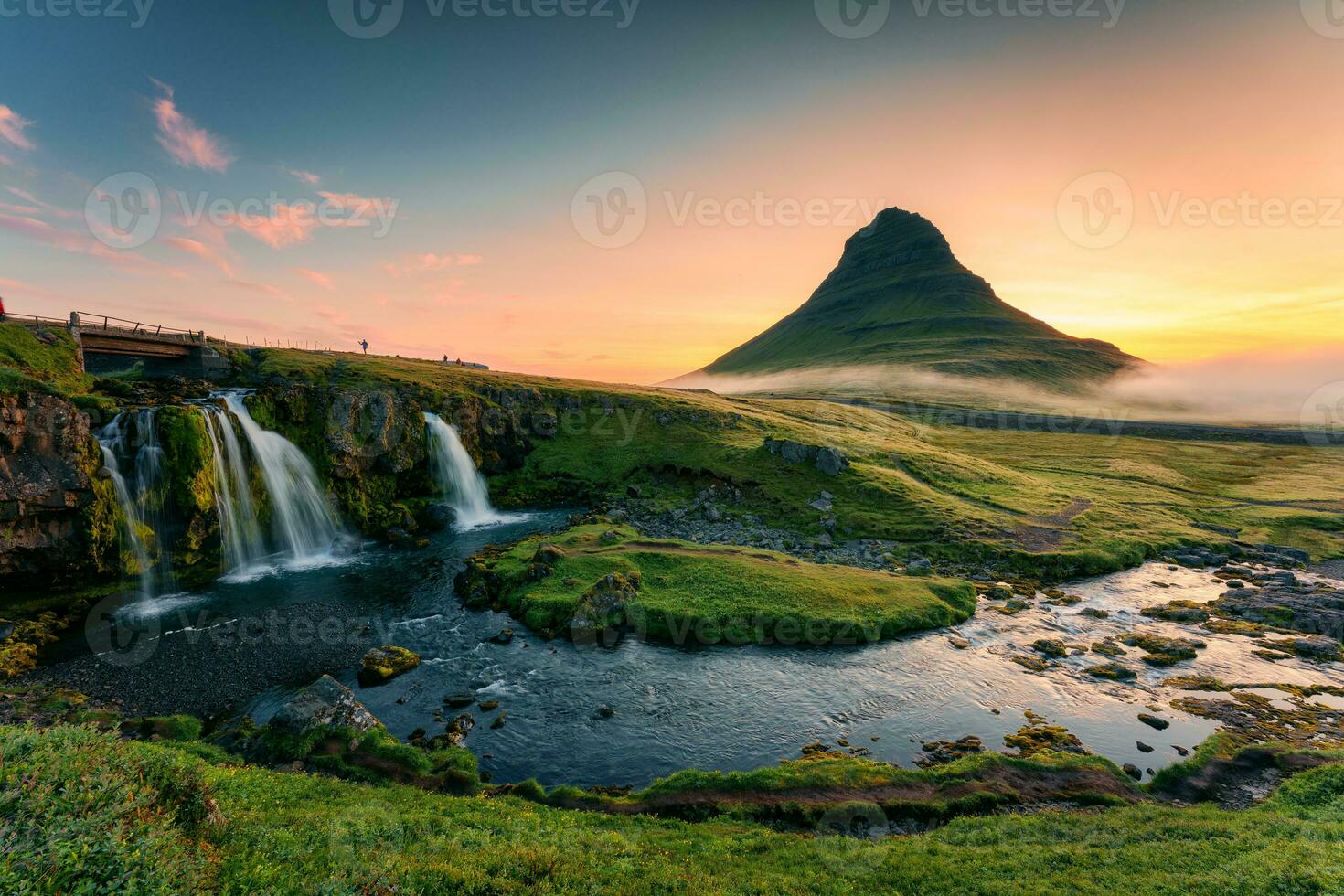 Sunrise over volcanic Kirkjufell mountain with waterfall flowing and foggy in summer at Iceland photo