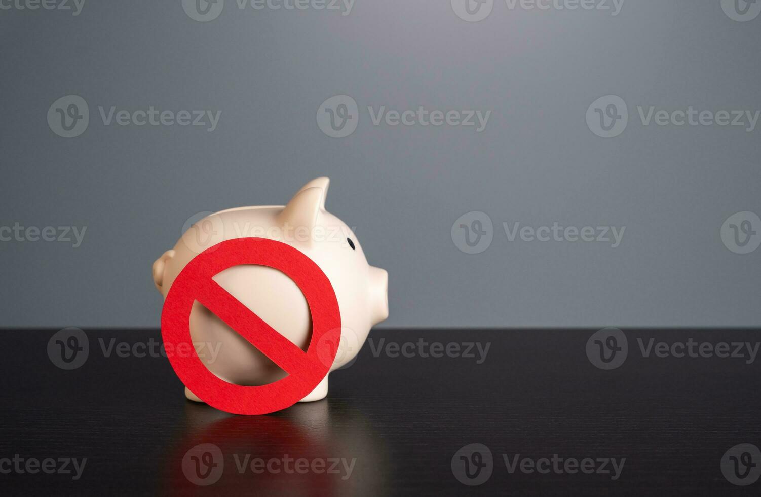 Piggy bank under the symbol of prohibition. Sanctions. Capital outflow restrictions. Freezing savings. Lack of funds. Refusal of savings in favor of investments. photo