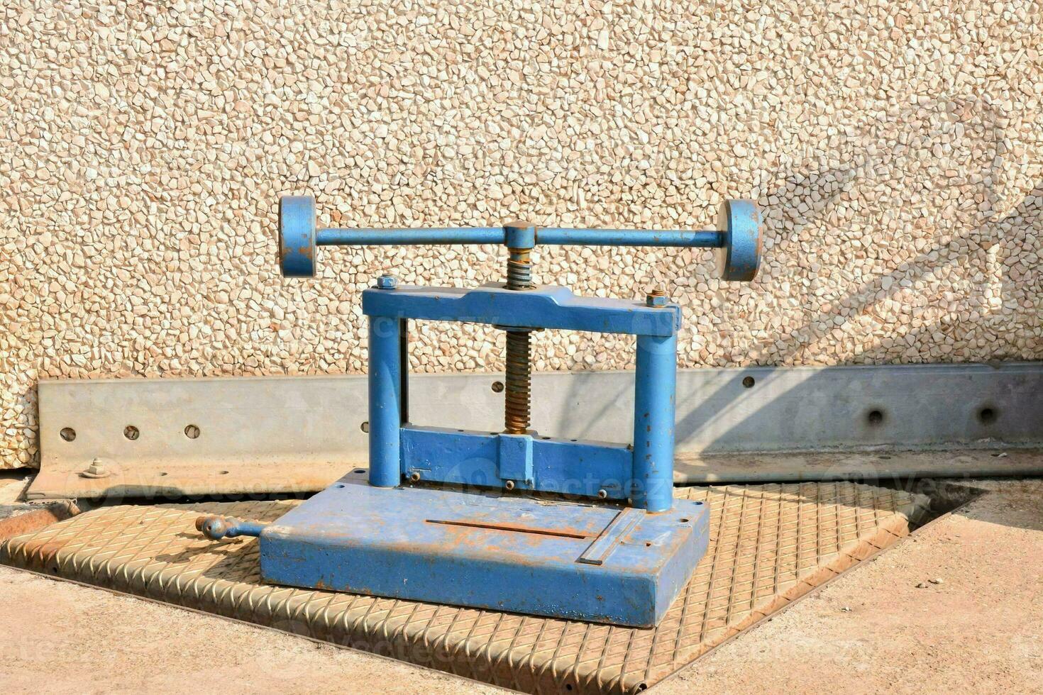 a blue machine with wheels on it sitting on a cement floor photo