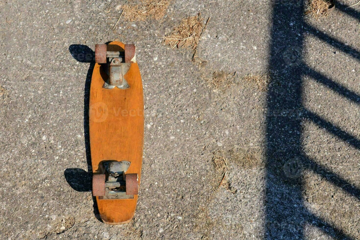 a skateboard is sitting on the ground next to a fence photo