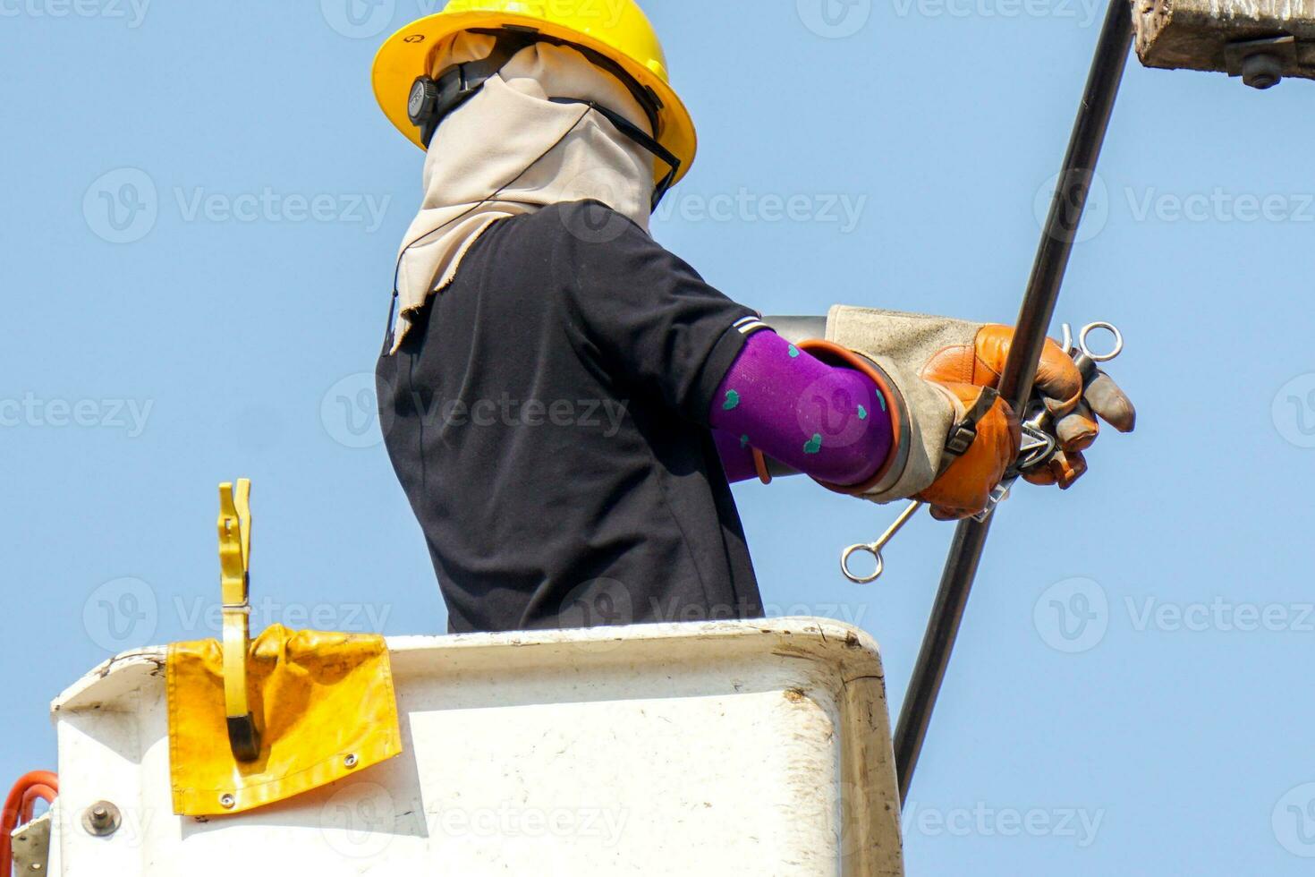 electricistas de primer plano que trabajan en el teleférico para reparar la línea eléctrica bajo un fondo de cielo azul claro. foto