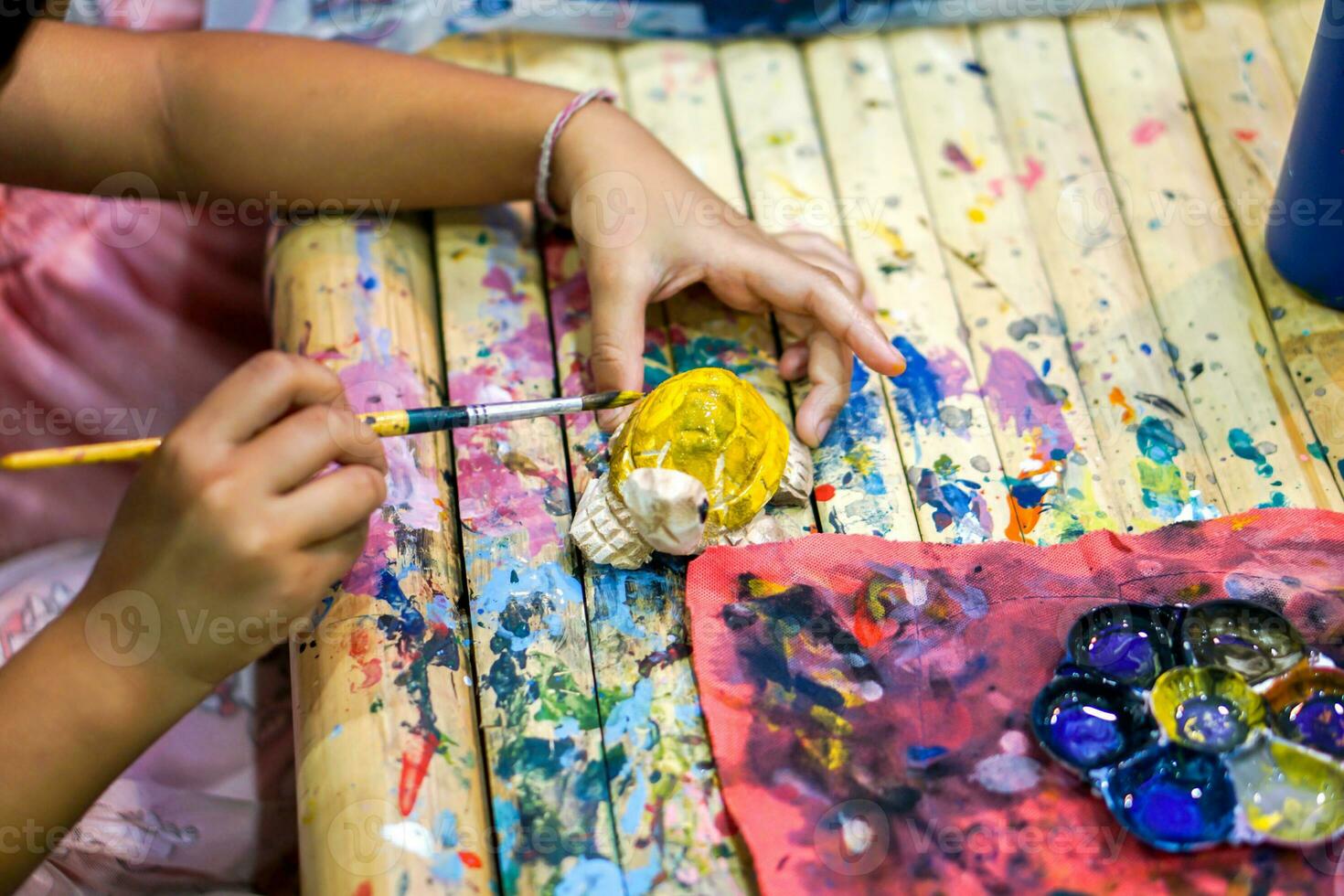 Closeup hands of art students holding paint brush study and learning paint on wood animal doll in the art classroom. photo