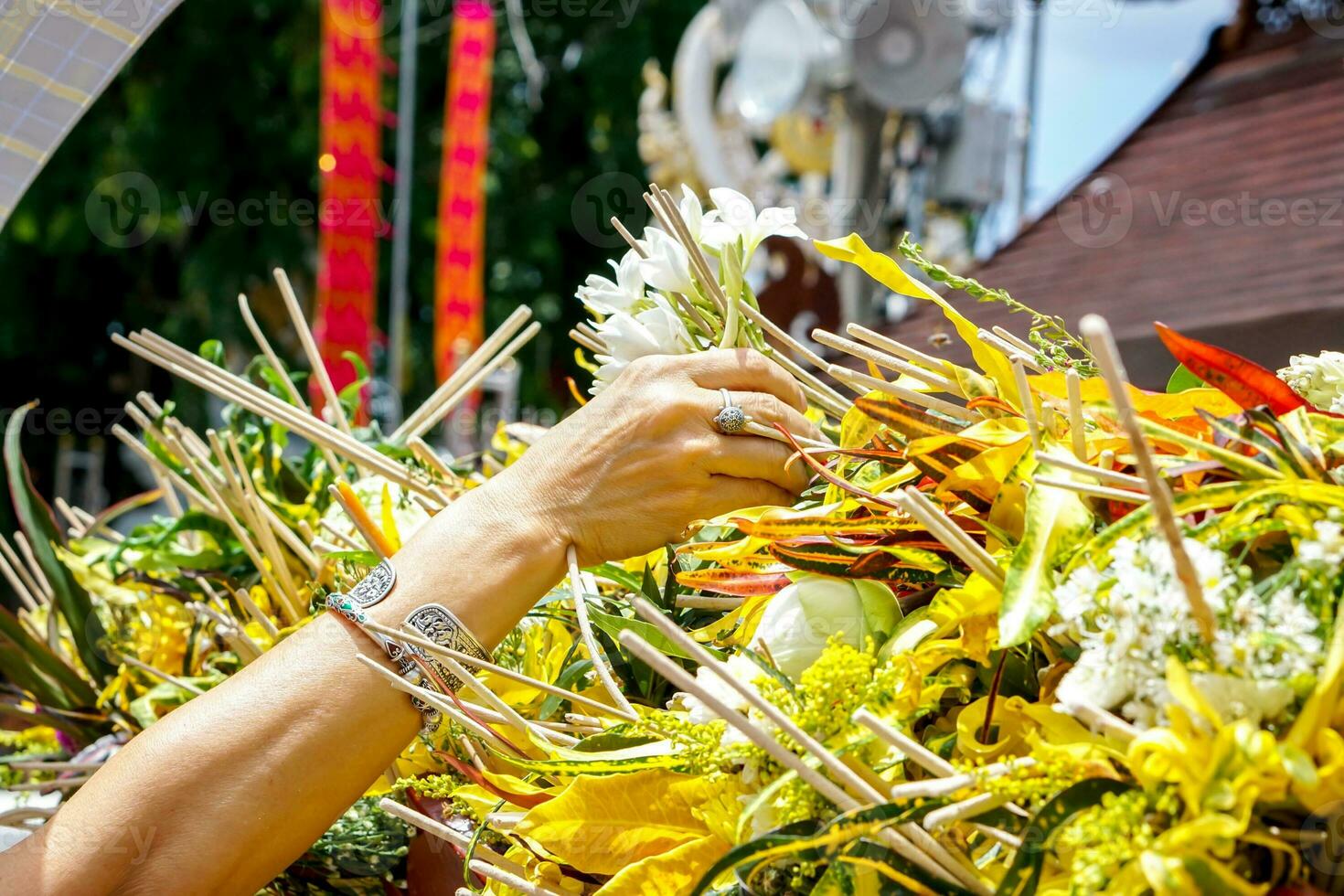 Closeup hand of people put a fragrant flowers with incense on heap of flowers in the Thai Lanna dedicate a bouquet of flowers to worship the Buddha tradition. photo