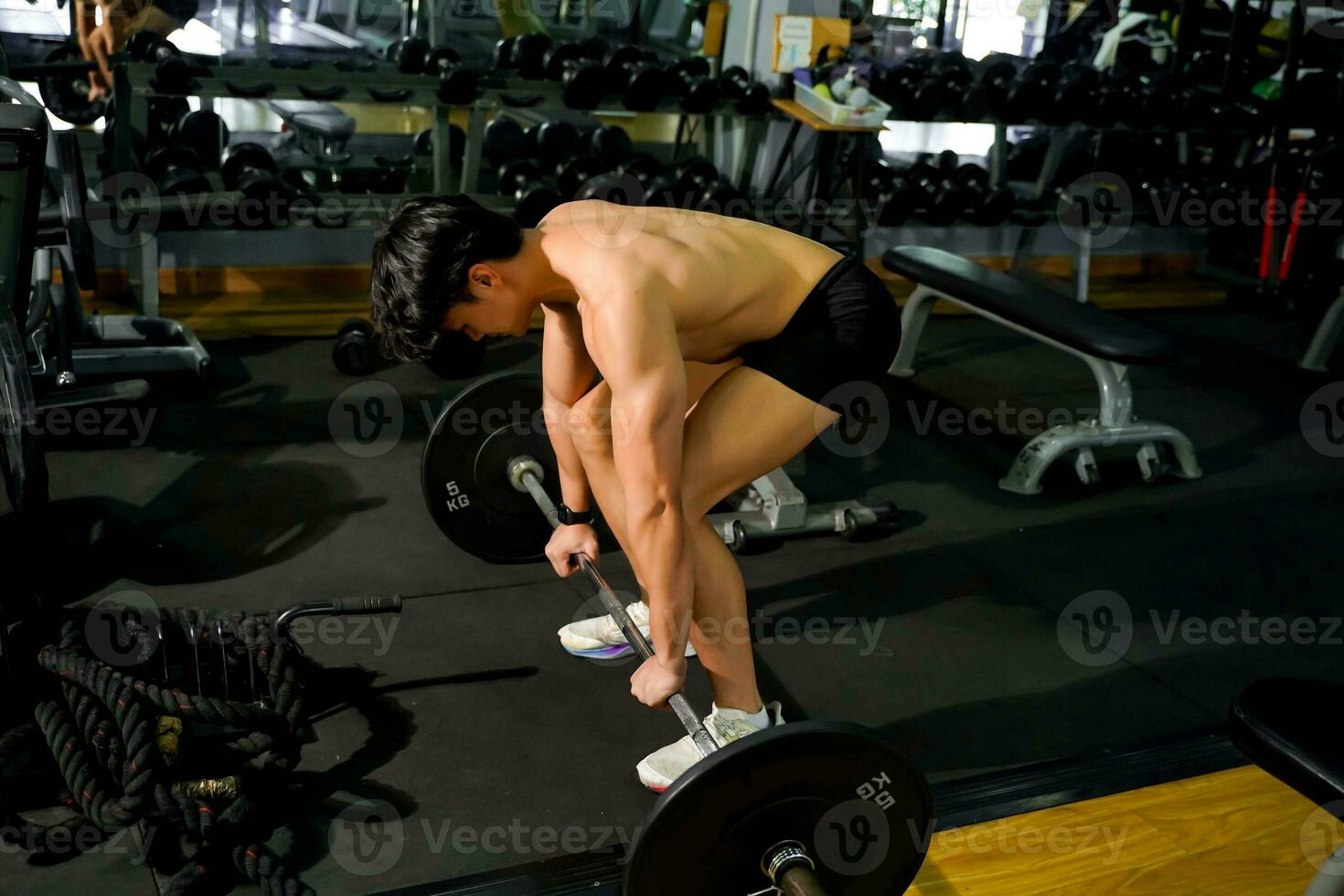 Side view of Asian handsome man  with perfect body playing weight training at fitness center. photo