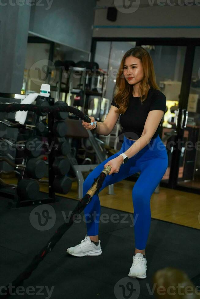 Closeup Asian young female workout training the battle rope in fitness center. photo