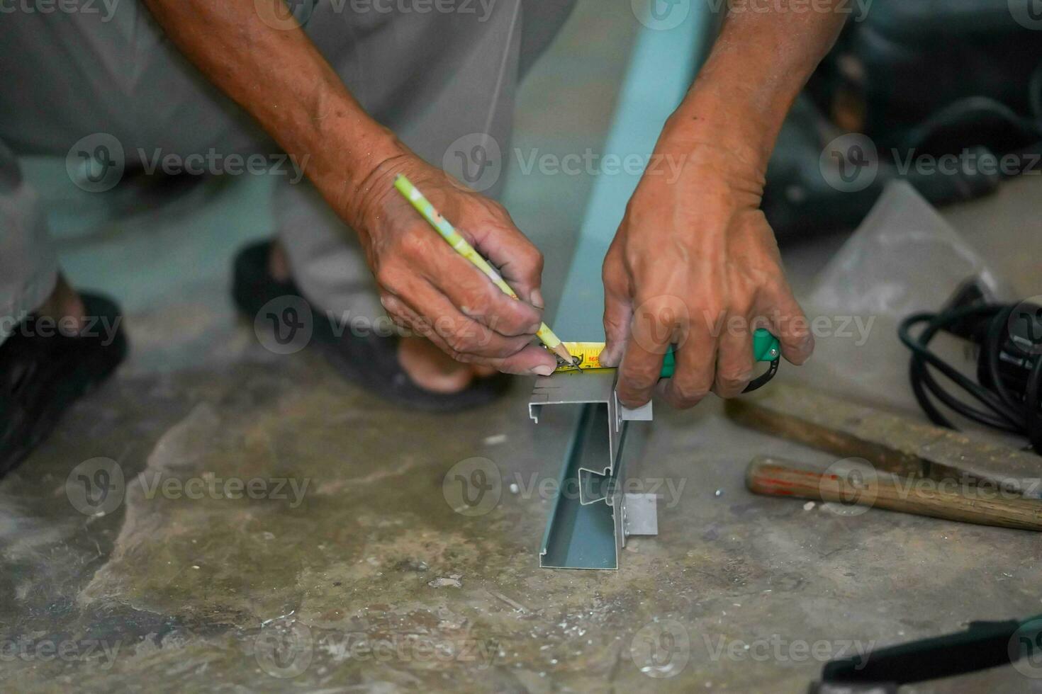 Closeup hands of builder using a pencil marks out the details before cutting aluminum lumber at construction site. photo