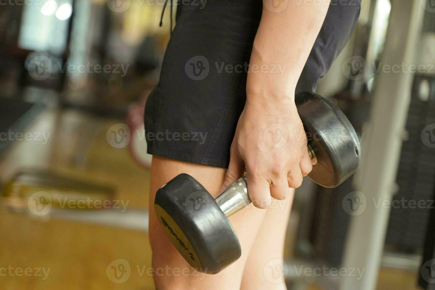 Closeup and crop hand of people holding a dumbbell at fitness center and blurred background. photo
