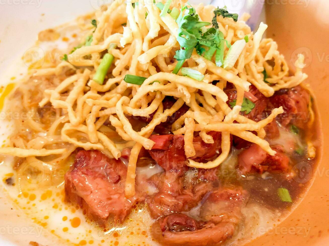 Top view and closeup Thai northern red curry noodle with beef stew and fried eggs noodles., Delicious thai northern food. photo