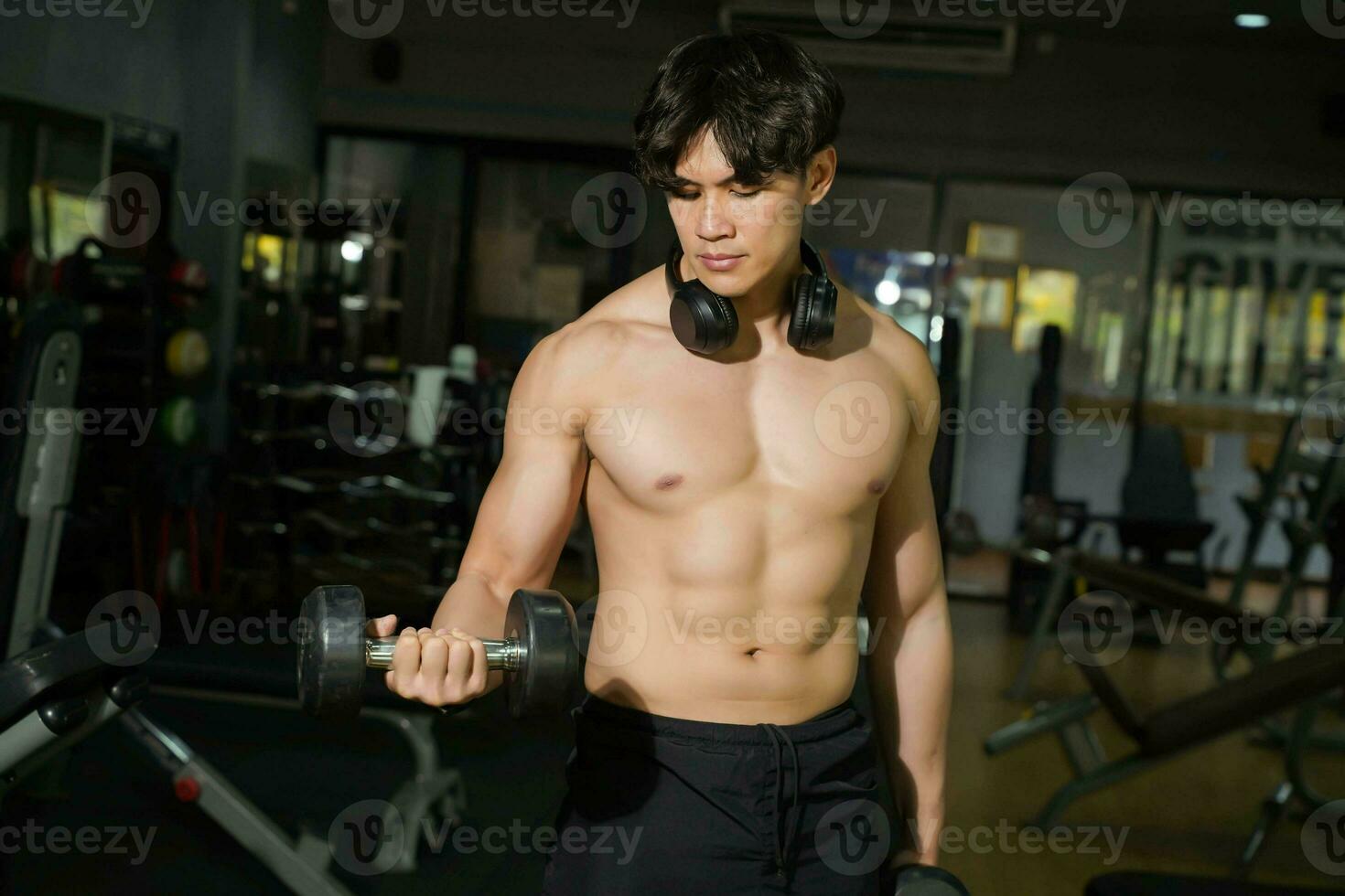 Asian handsome man  with perfect body playing weight training at fitness center. photo