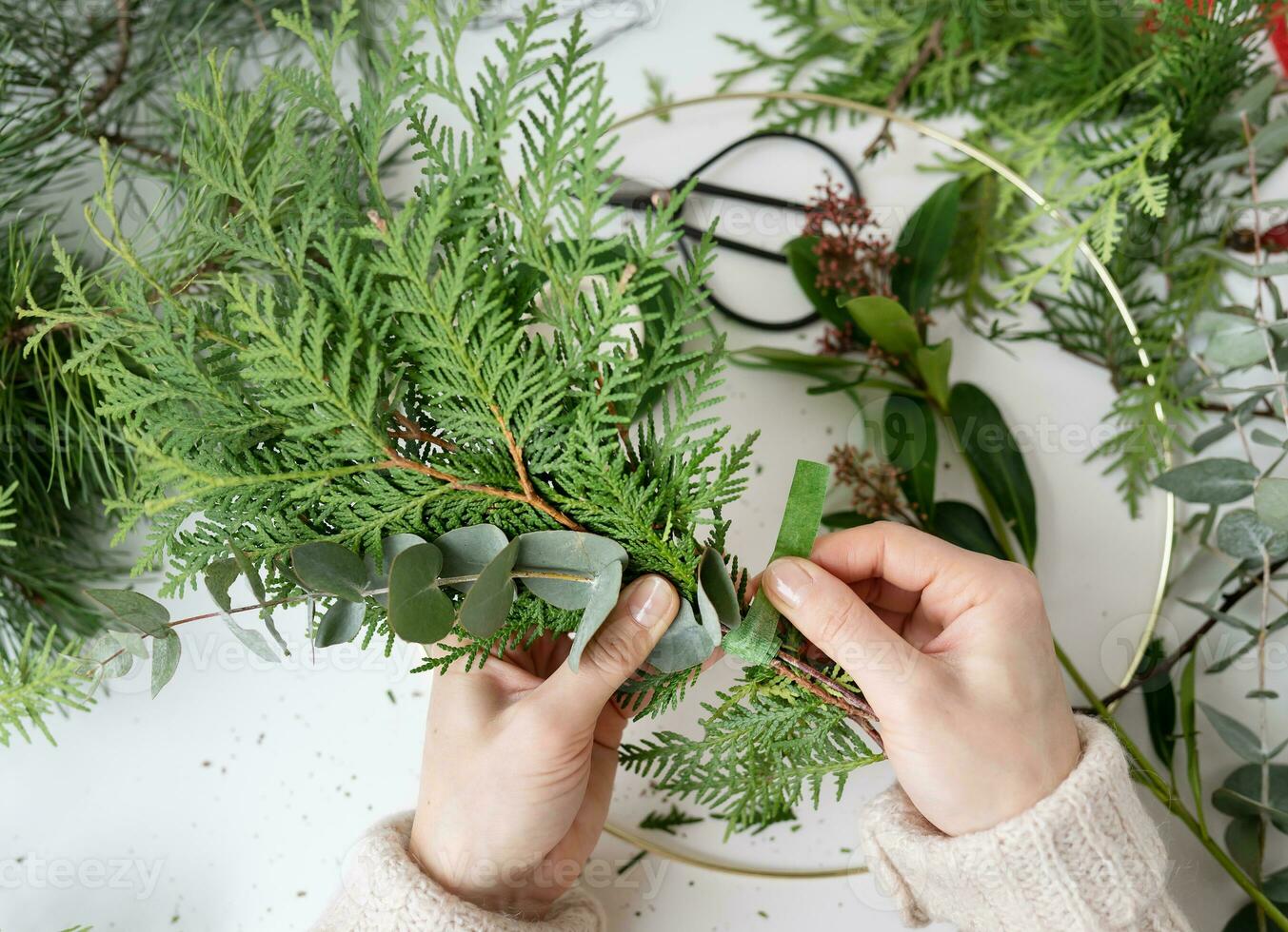 The process of making a Christmas wreath from needles, thuja, shimia, rosehip, pine twigs, chopped twigs for the wreath. The concept of preparation for Christmas and New Year. photo