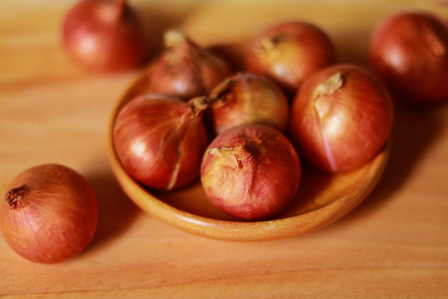 Shallot onions in a wooden bowl on a wooden background. photo