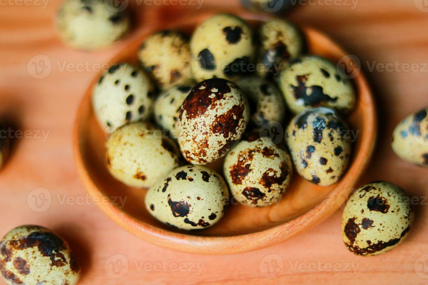 Quail eggs in a wooden bowl on a wooden background. Selective focus. photo