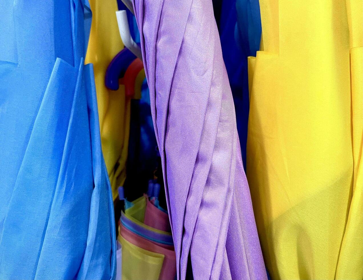 Vibrant blue, purple, and yellow closed umbrella roll in store isolated on horizontal photography ratio photo