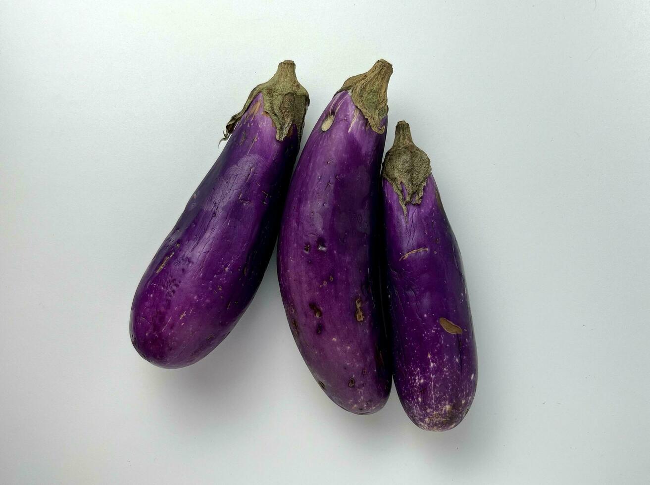 Not so fresh purple vegetable, eggplant. Three pieces of half good and half bad food ingredients with damaged and scratched skin object photography isolated on plain white background. photo