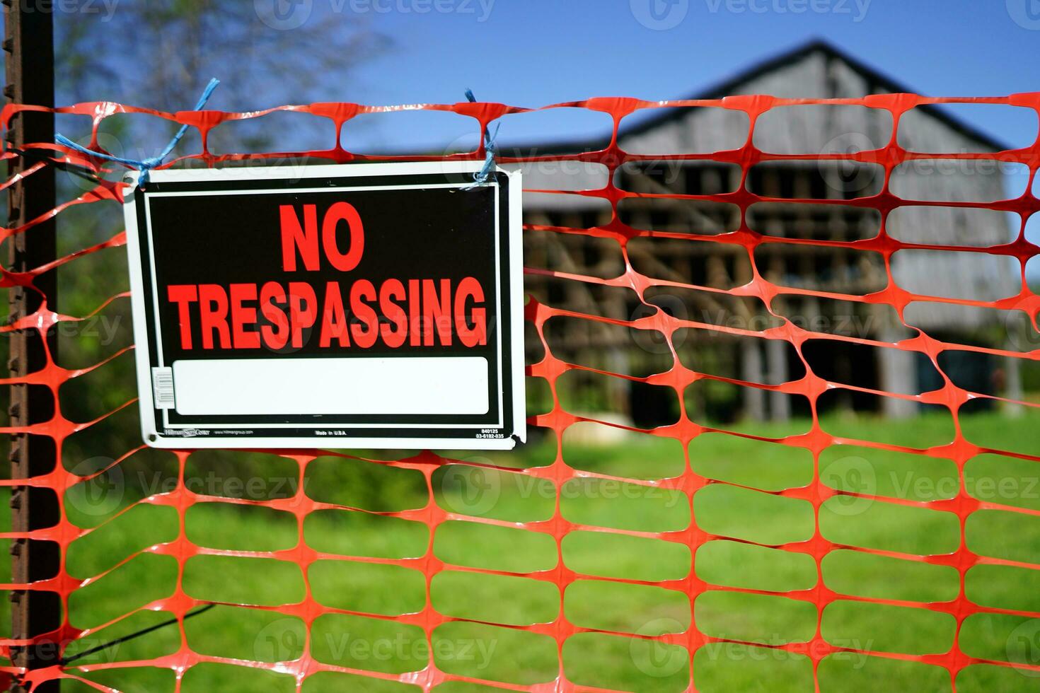 No trespassing sign on a construction fence around an old worn out country style pole barn photo