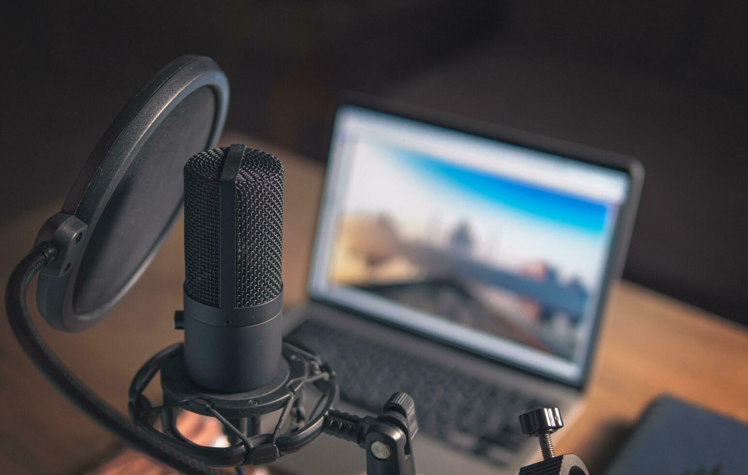 Home studio for podcasts. Large Microphone, laptop and notebooks on the table. Close-up. Cinematic photo