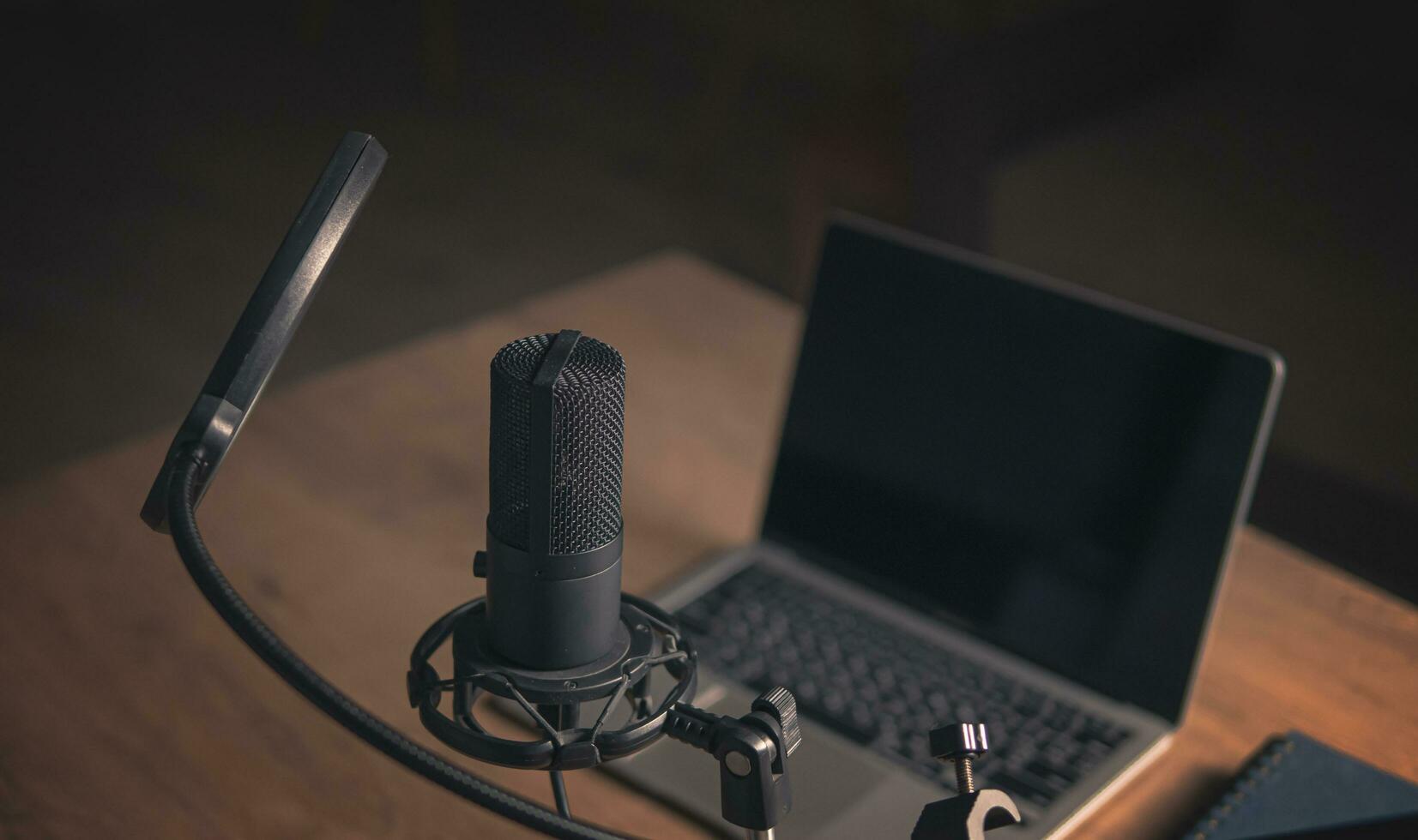 Home studio for podcasts. Large Microphone, laptop and notebooks on the table. Close-up. Cinematic style photo