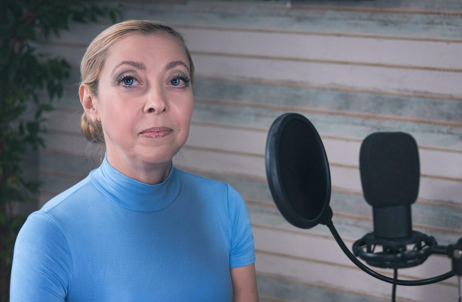 Beautiful girl preparing for a podcast with a microphone and ficus in the background photo