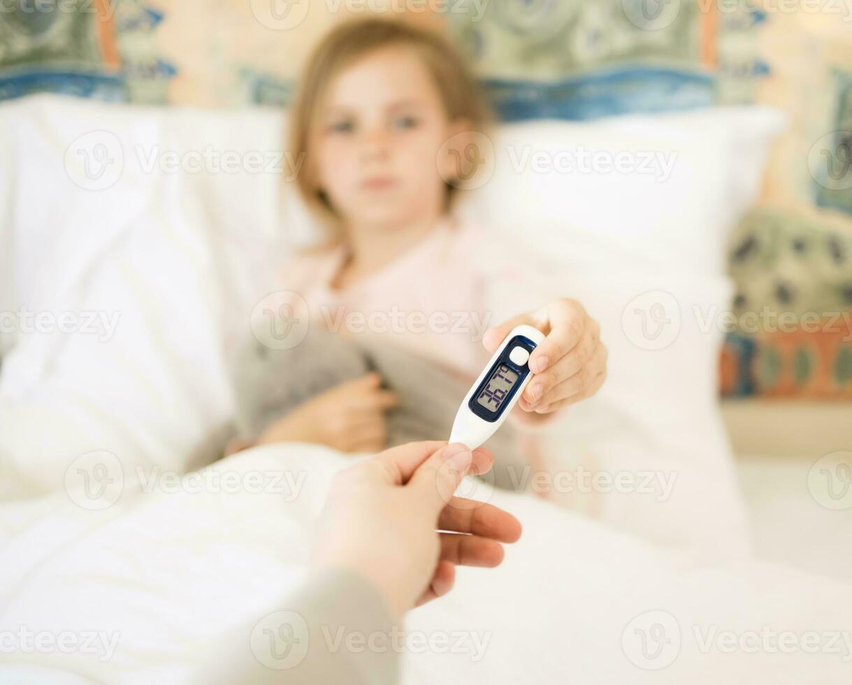 recuperación después enfermedad. pequeño niña dando su madre digital termómetro después medición temperatura. foto