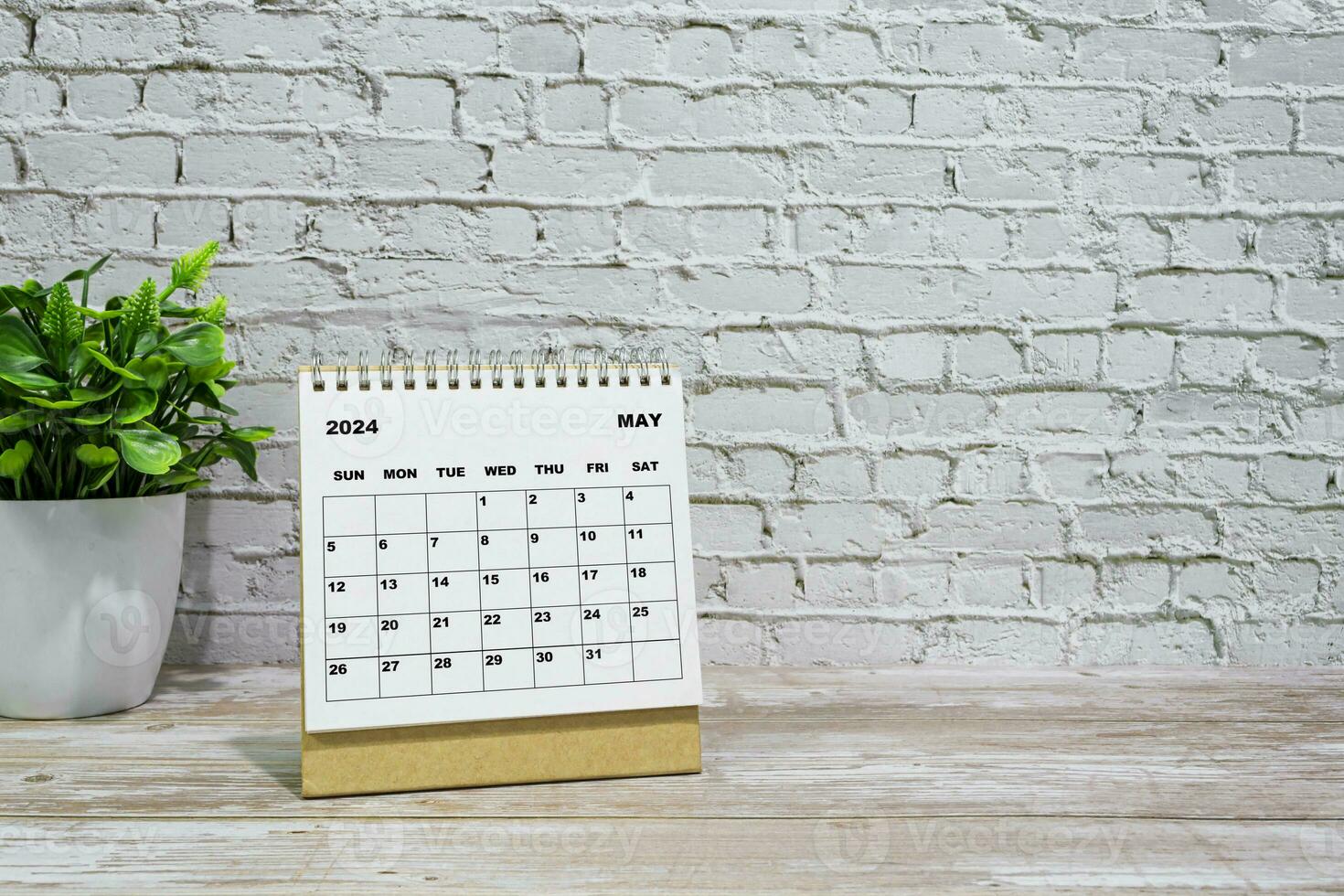 White May 2024 calendar on office wooden desk with potted plant. photo