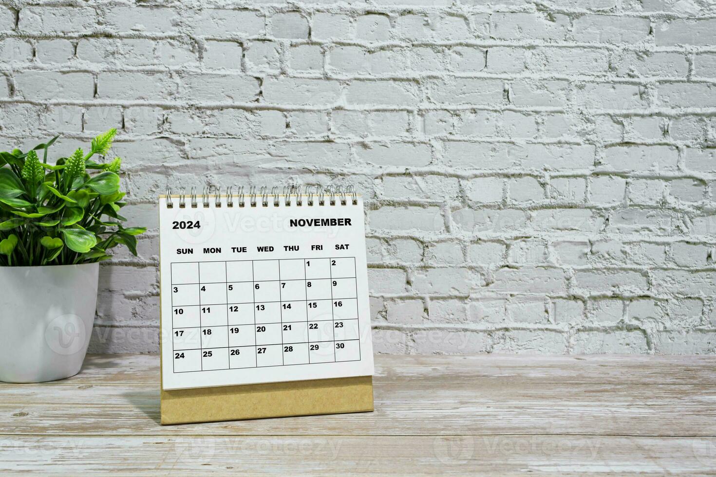 blanco noviembre 2024 calendario en oficina de madera escritorio con en conserva planta. foto