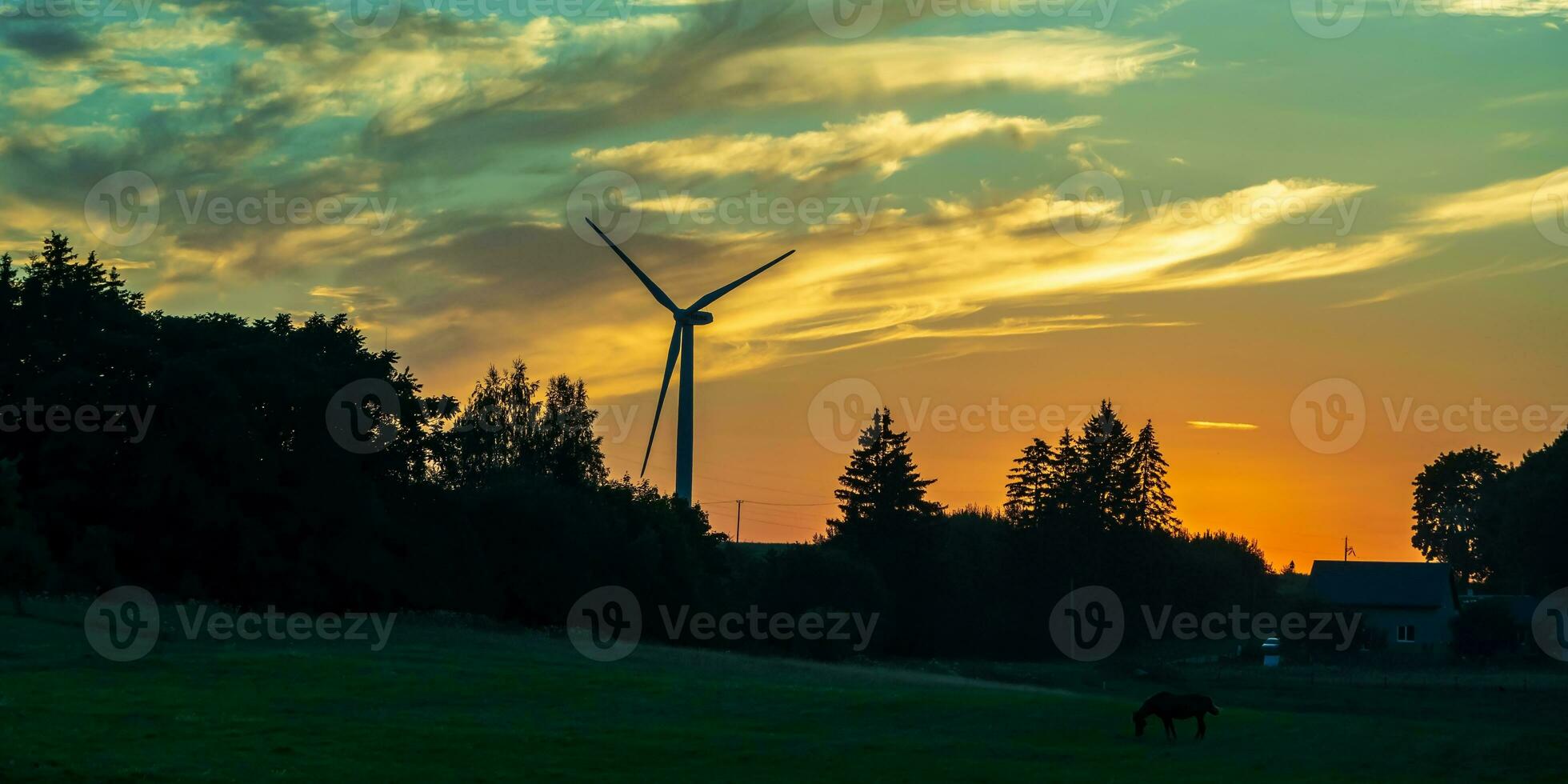 silhouettes of the rotating blades of a windmill propeller against the sunset sky. Wind energy production. Clean green energy. photo