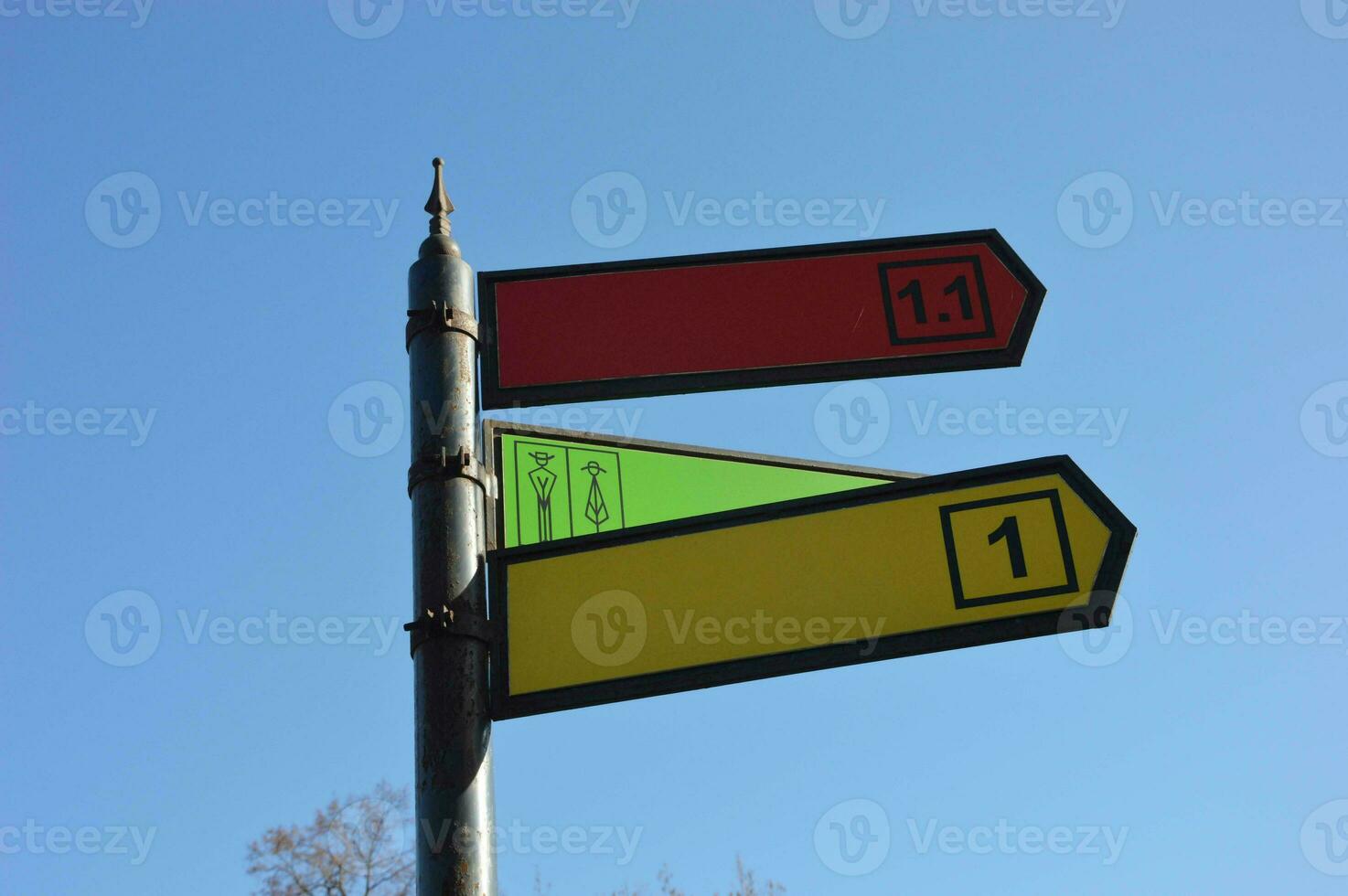 Metal street sign pointer. A pillar with colored direction arrows and destination numbers against the sky. Place for names. photo