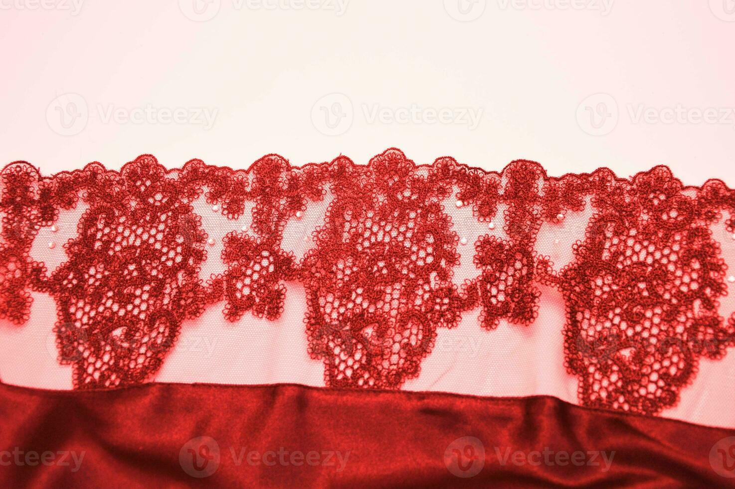 Red lace with an openwork pattern on a white background. Finishing element of lingerie, negligee. photo