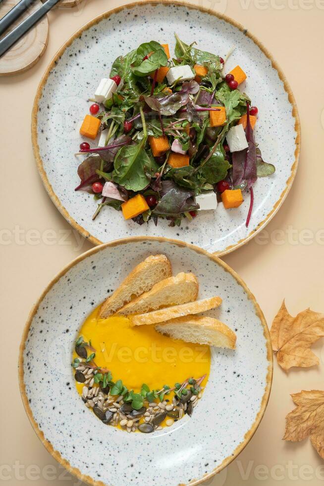 Pumpkin puree soup and pumpkin salad. Autumn menu top view, flat lay photo