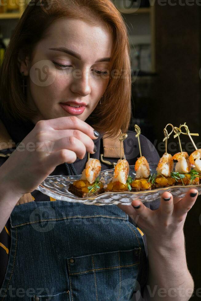Shrimp and mango chutney canapes in female fingers near open mouth. Mini sandwich eating photo