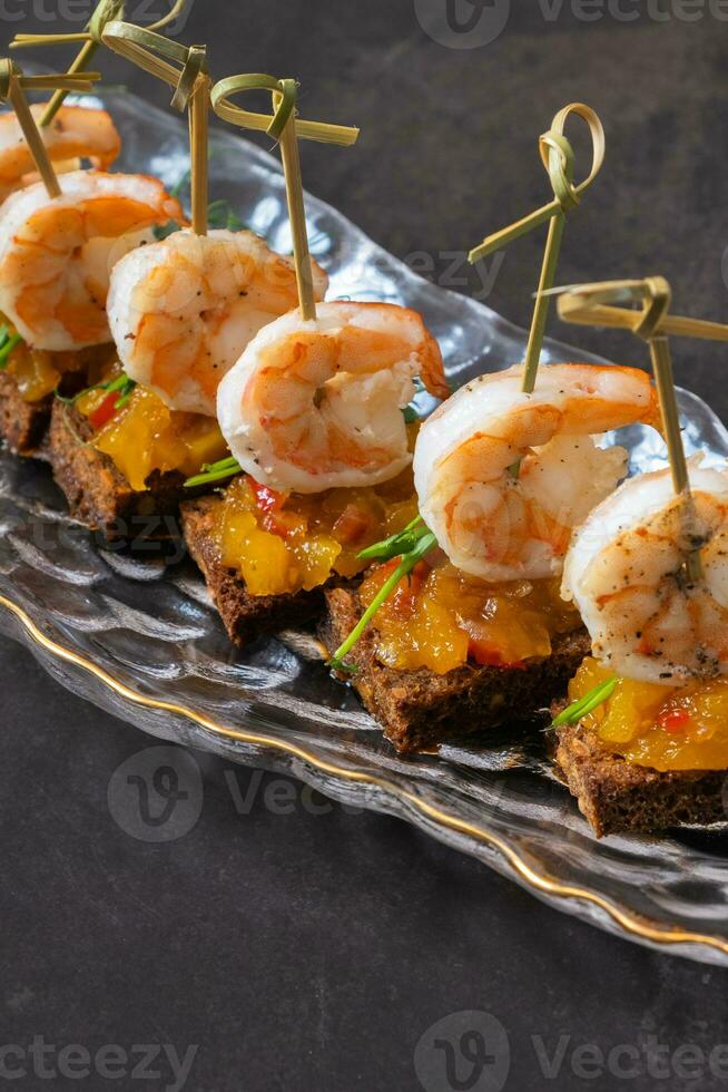 Close up shrimp and mango chutney canapes on dark background. Mini sandwich, catering concept photo