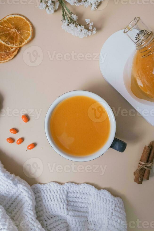 Cup and teapot of sea buckthorn tea and macaroon flat lay, top view. Cozy autumn winter time photo