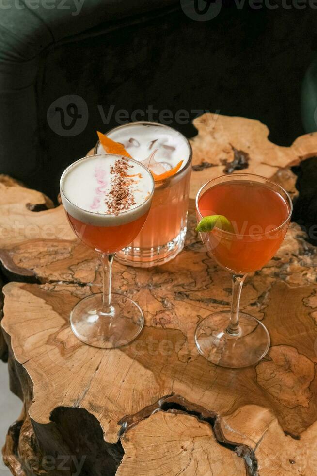 Four bright alcoholic cocktails in glasses on wooden cafeteria table photo