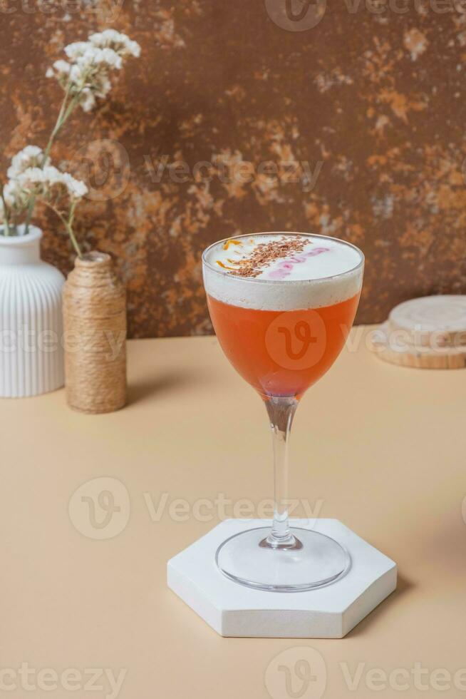 Bright alcoholic cocktail in stemmed glass on podium or pedestal with dry flowers in vases. photo