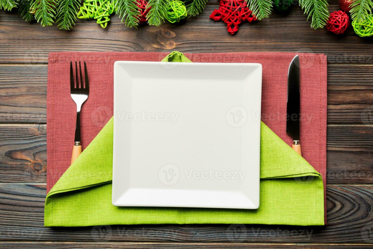 Top view of New Year dinner on festive wooden background. Composition of plate, fork, knife, fir tree and decorations. Merry Christmas concept photo