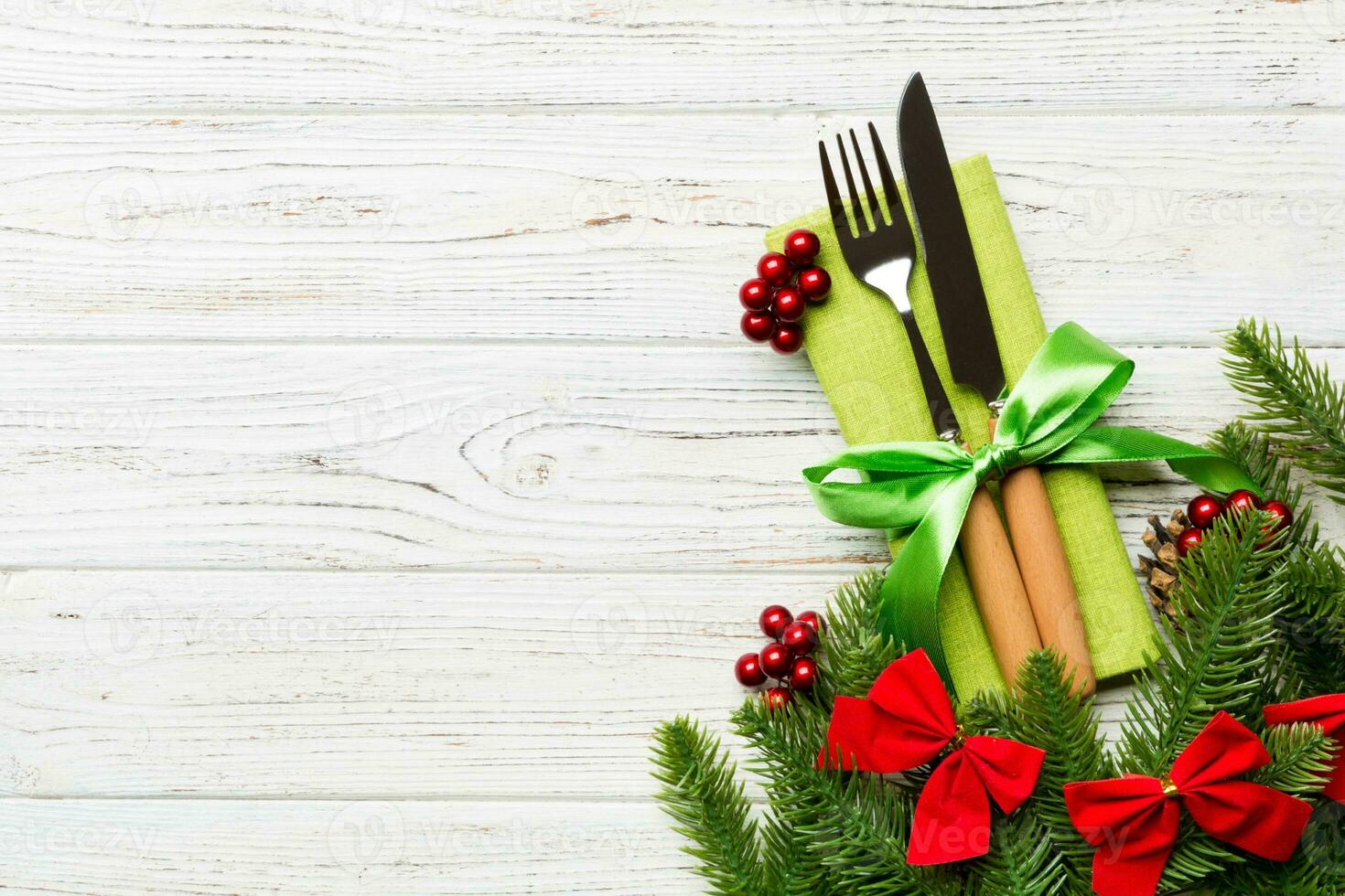 Top view of christmas decorations on wooden background. Fork and knife on napkin tied up with ribbon and empty space for your design. New year pattern concept photo