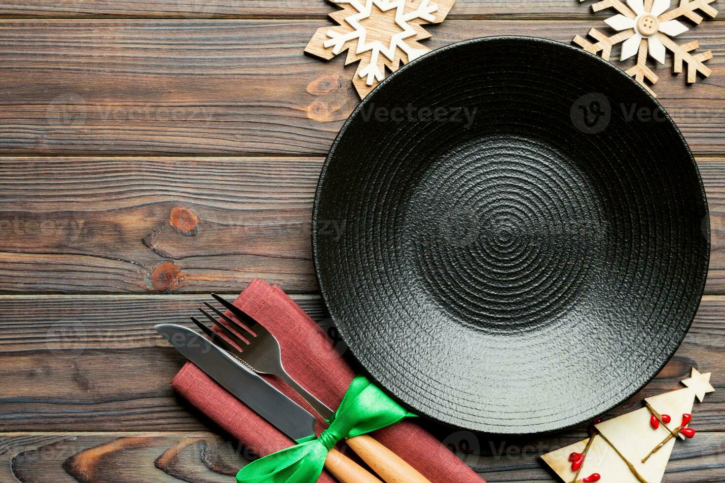 Top view of plate, fork and knife served on Christmas decorated wooden background. New Year Eve concept with copy space photo