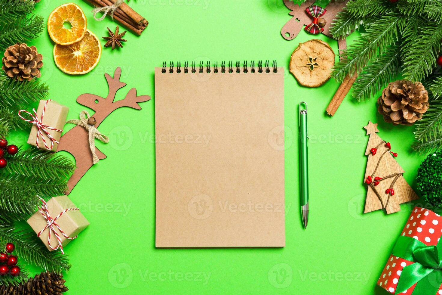 Top view of notebook on green background made of Christmas decorations. New Year time concept photo