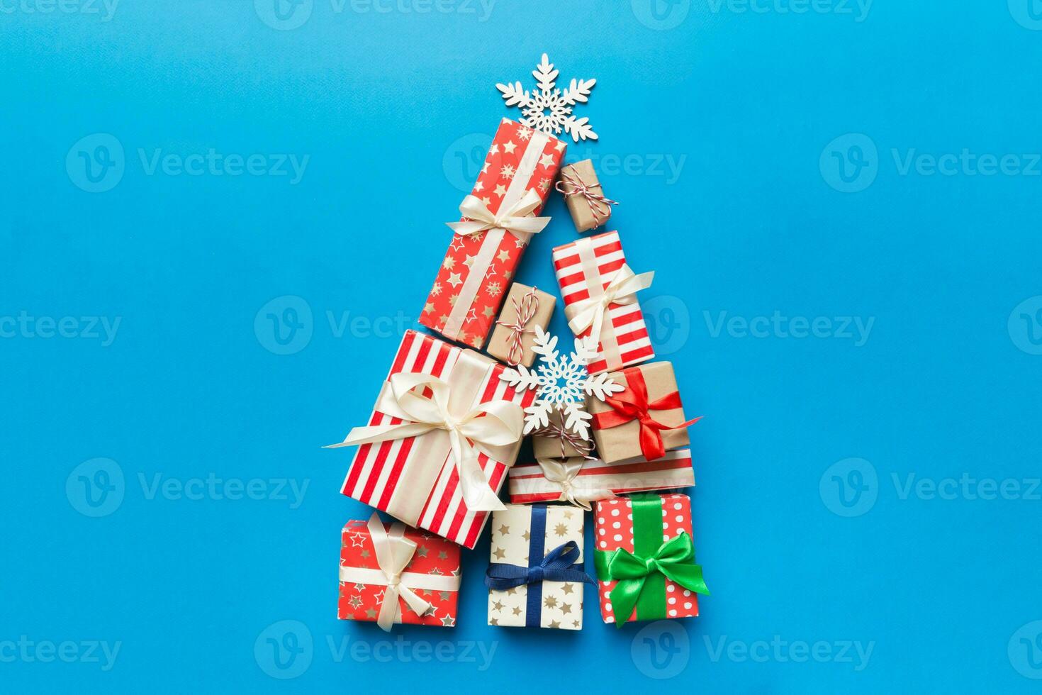Christmas tree made of beautifuly wrapped presents on colored background, view from above. New Year gift box minimal concept with copy space photo