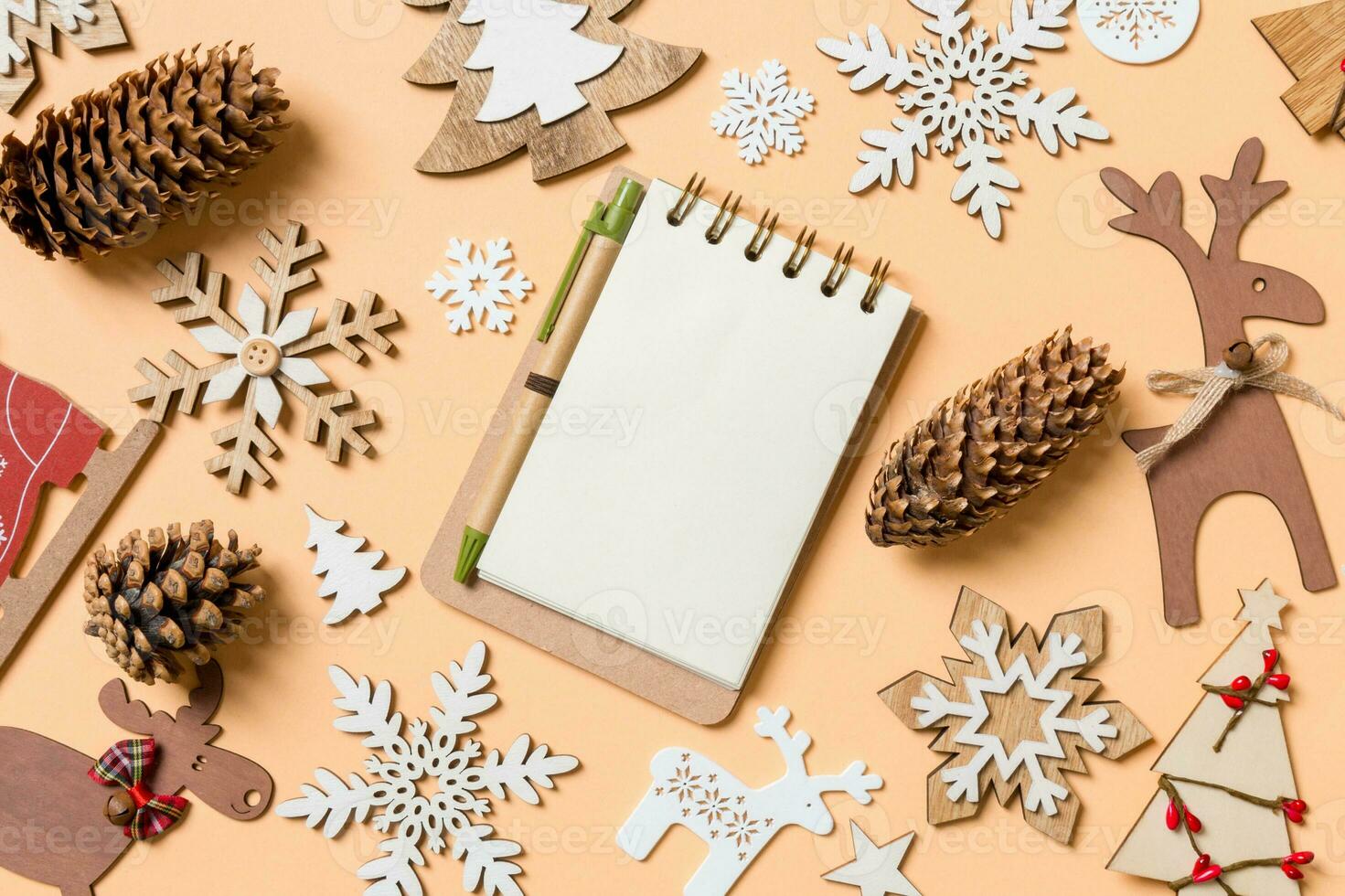 Top view of notebook surrounded with New Year toys and decorations on orange background. Christmas time concept photo