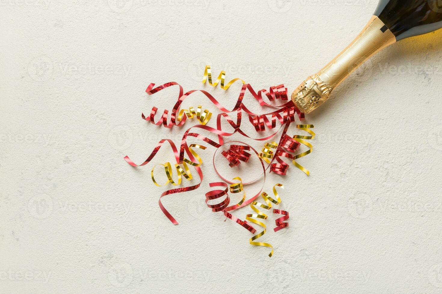 Creative flat lay composition with bottle of champagne and space for text on color background. Champagne bottle with colorful party streamers. holiday or christmas concept photo