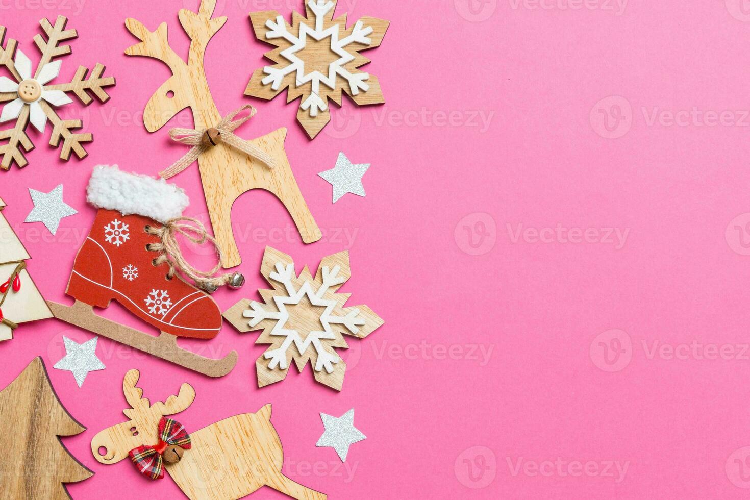 Top view of pink background decorated with festive toys and Christmas symbols reindeers and New Year trees. Holiday concept with copy space photo