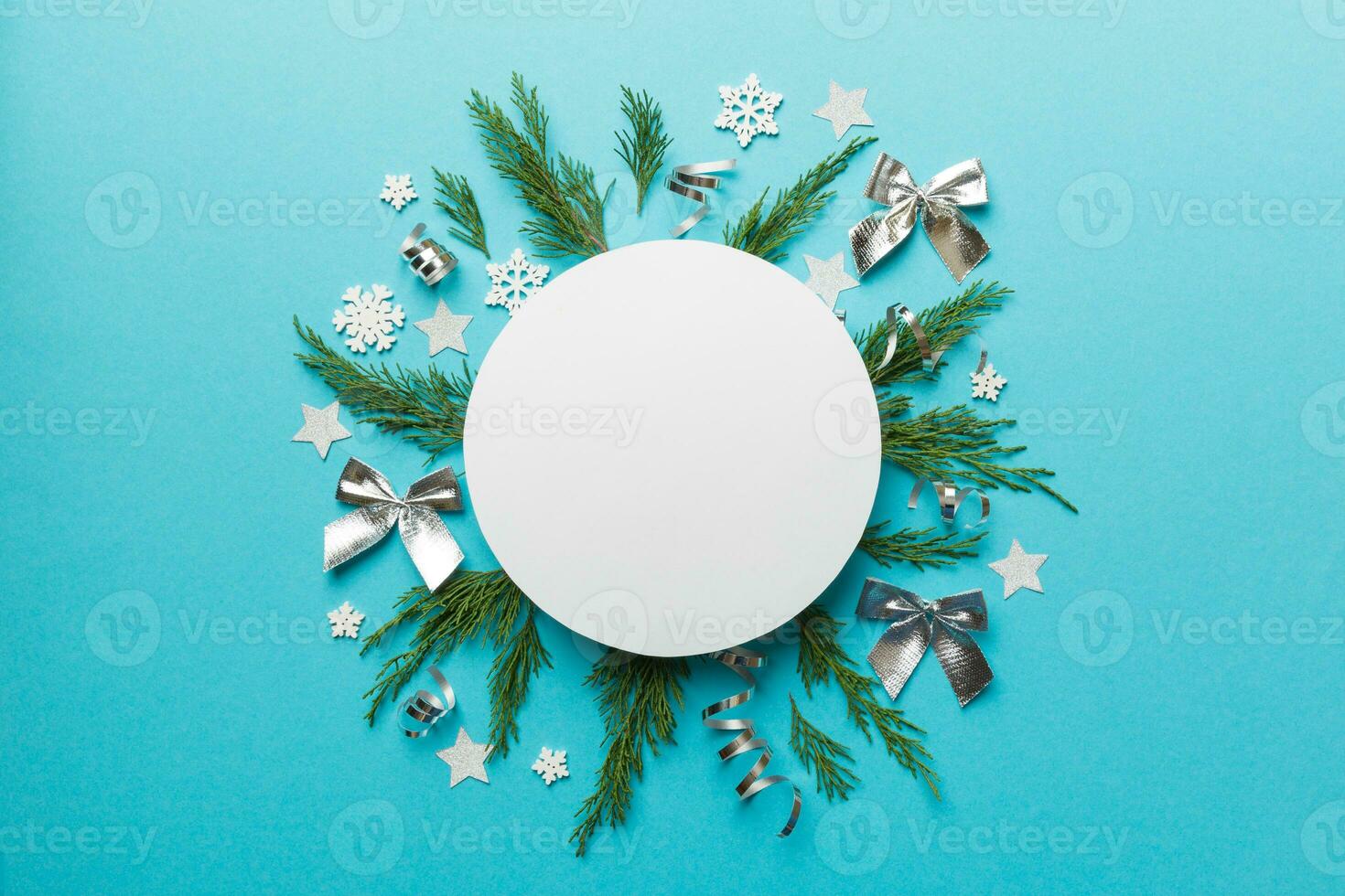 Flat lay Christmas composition. Round Paper blank, pine tree branches, christmas decorations on Colored background. Top view, copy space for text photo