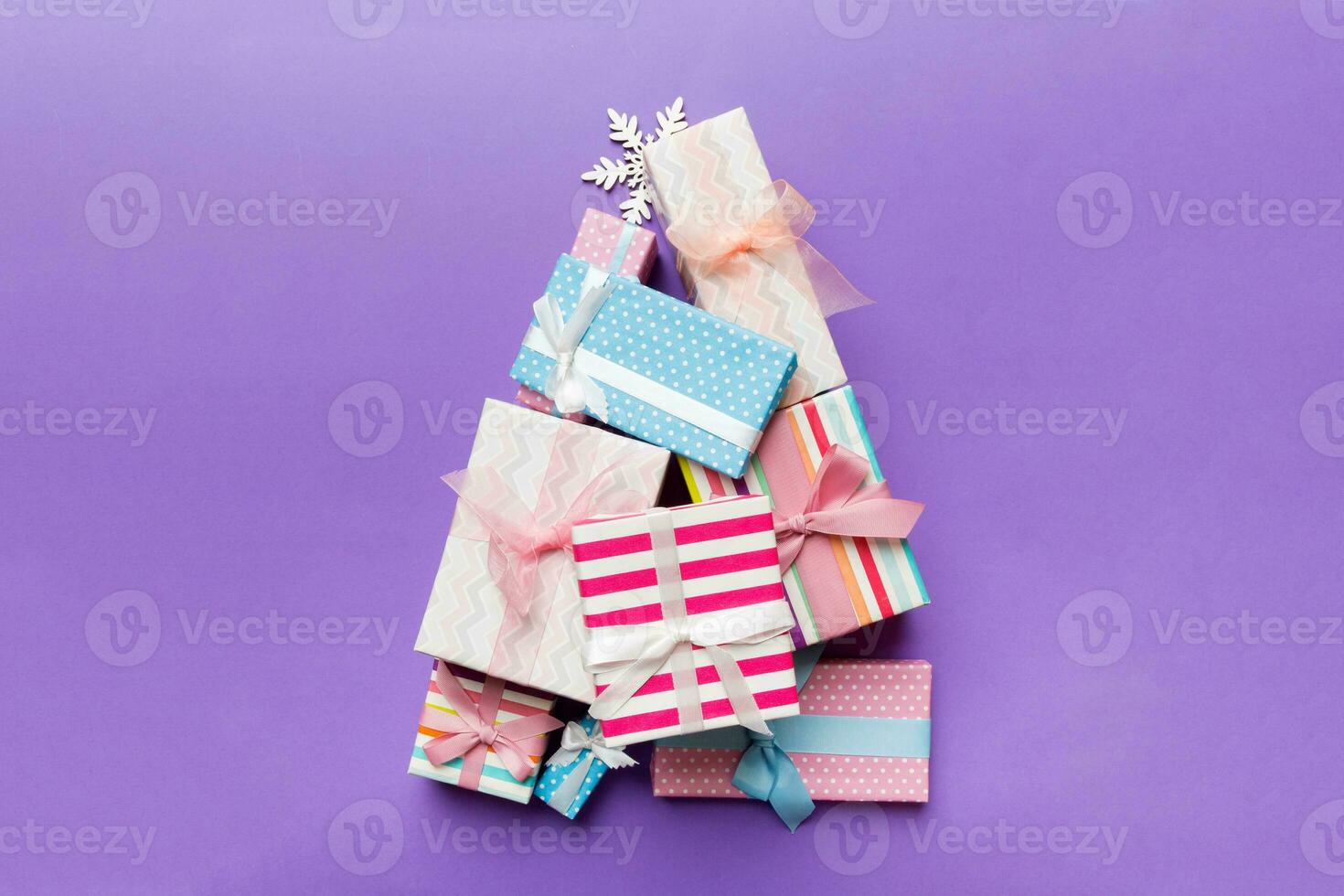 Christmas tree made of beautifuly wrapped presents on colored background, view from above. New Year gift box minimal concept with copy space photo