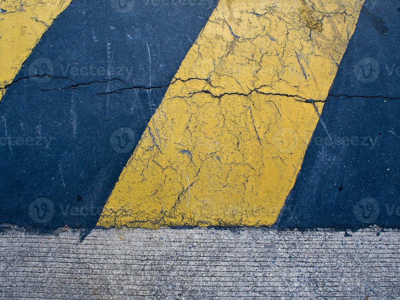 Yellow and black color strip as warning sign on the concrete speed hump on road photo