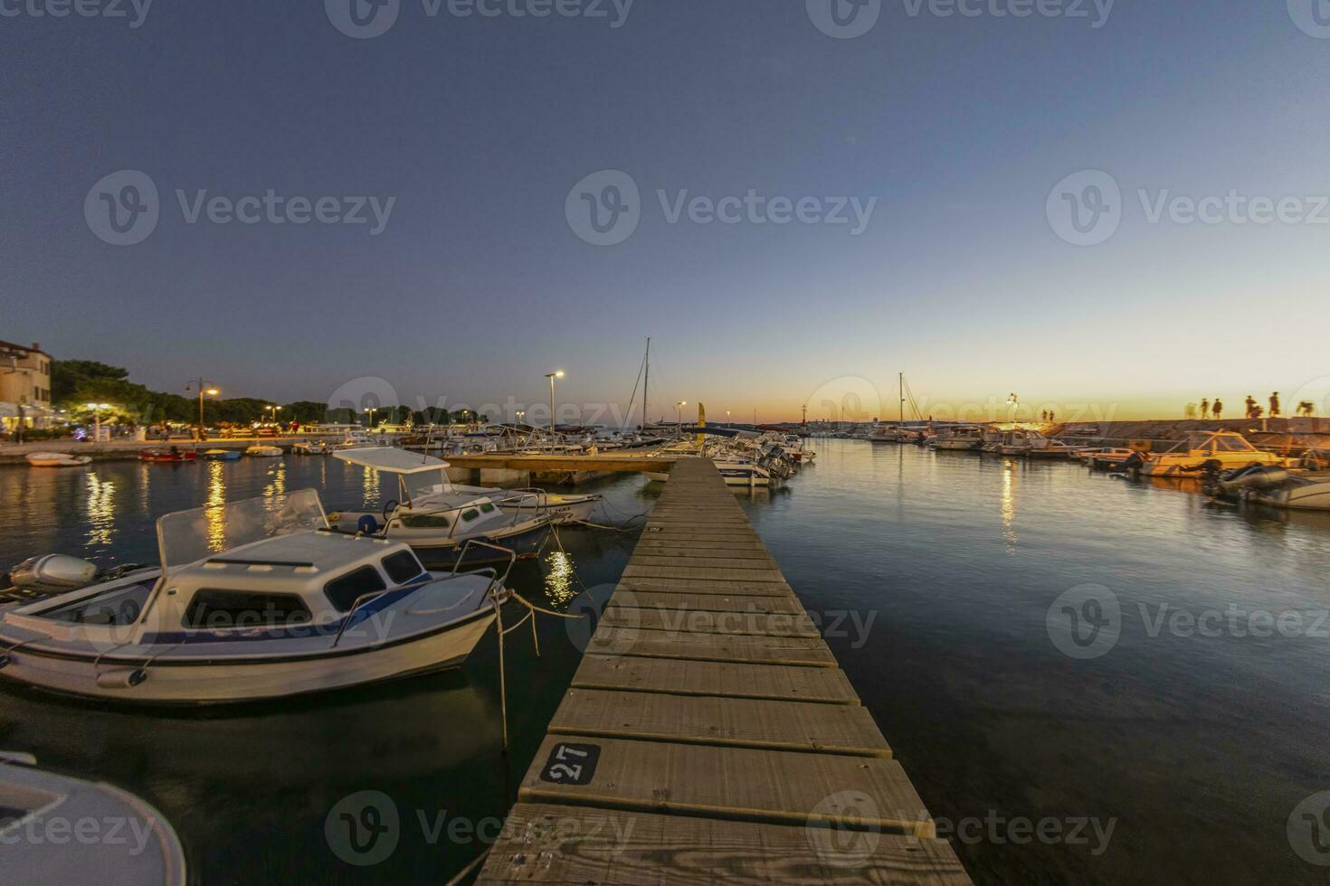 Sunset in the harbor of the Croatian coastal village of Fazana over a jetty for boats in summer evening photo