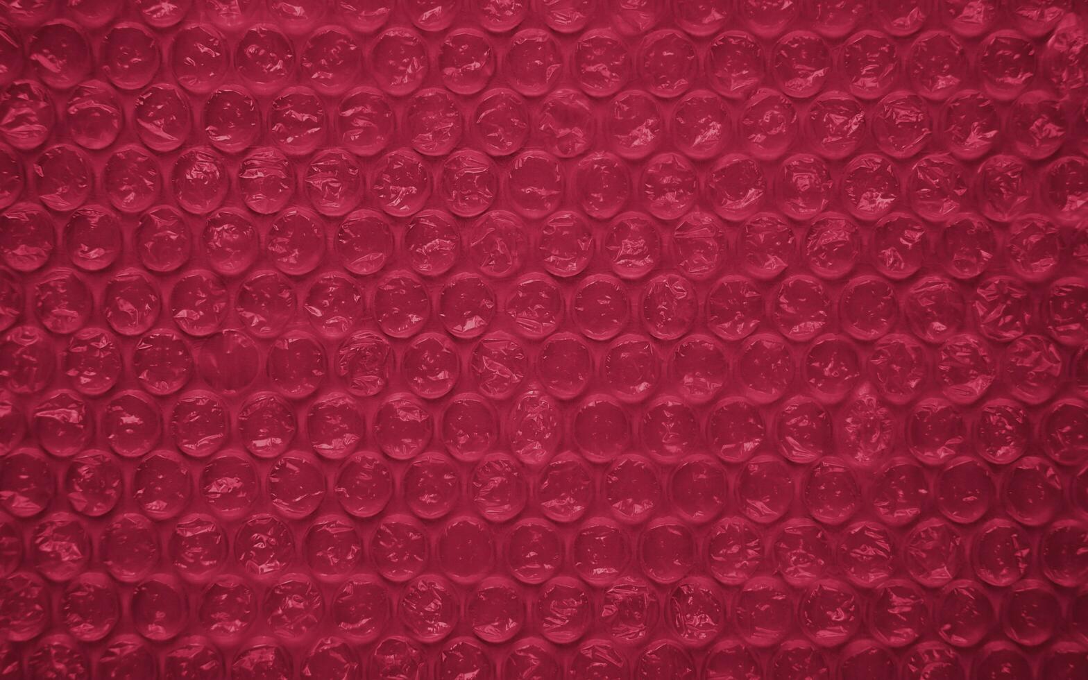 The texture of the packaging air-bubble film colored in the color of the Year 2023 Viva Magenta 18-1750. Wallpaper. Banner. Close-up. Selective focus. photo